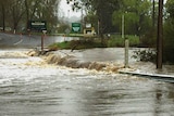 River flowing across a road, with Oakbank signage nearby.