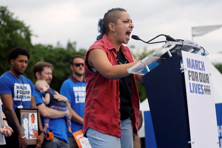 X Gonzalez stands at a podium giving a passionate speech at the Washington rally. 