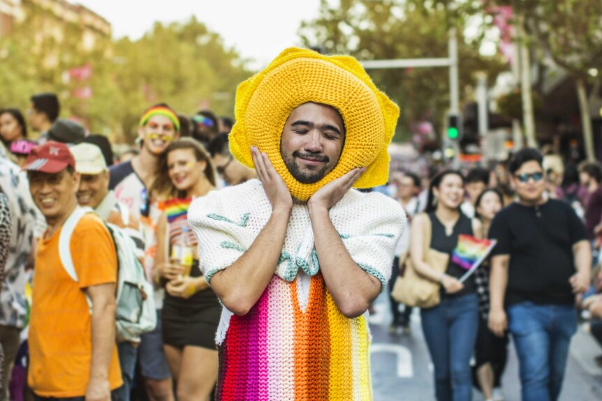 A young man in a rainbow crocheted outfit at the Mardi Gras parade