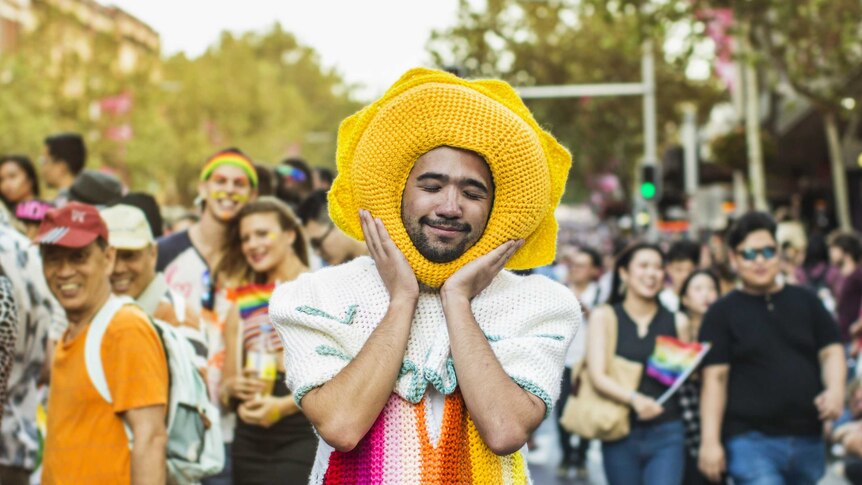A young man in a rainbow crocheted outfit at the Mardi Gras parade