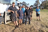 Farmers stand in front of the trucks they used to help.