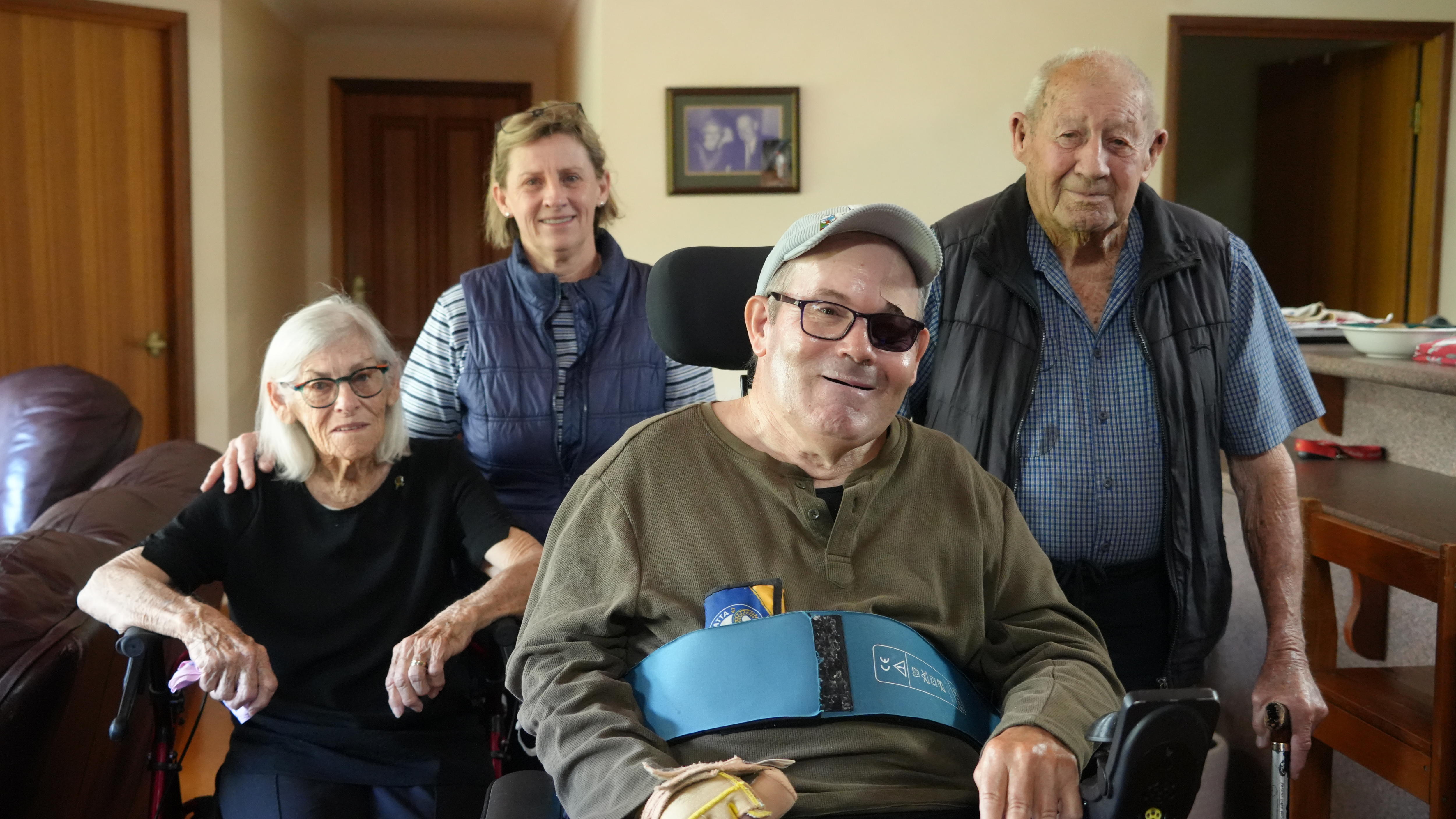 a man sits in a wheelchair with three family members behind him.