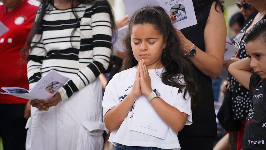 A girl holds her palms together in prayer.