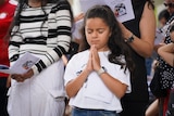A girl holds her palms together in prayer.