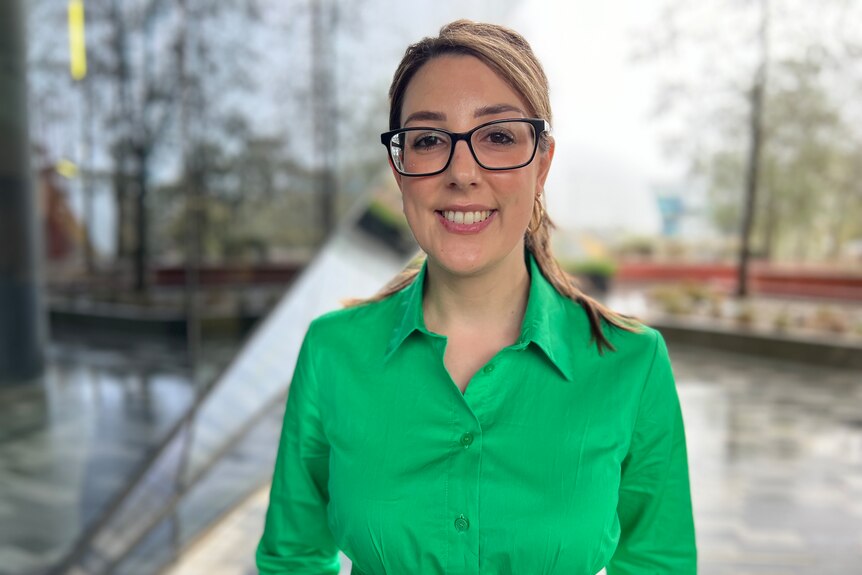 Danielle Snelling wears glasses and a green shirt, smiles.