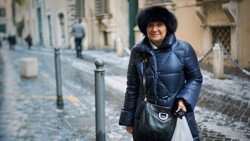 A woman stands smiling in an Italian street.