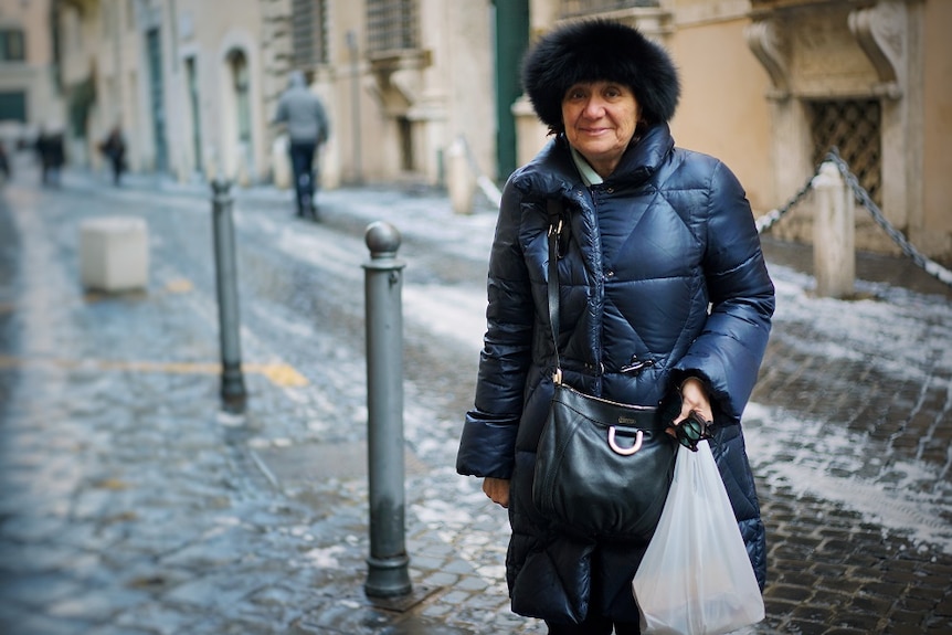 A woman stands smiling in an Italian street.