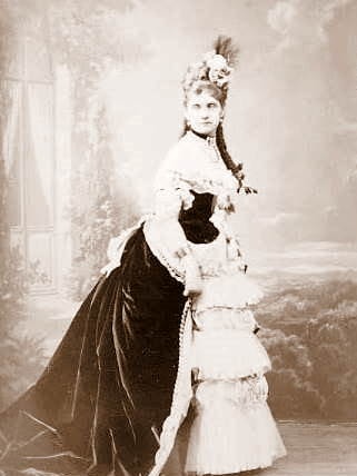 A photo from 1900 of a woman in elaborate dress.