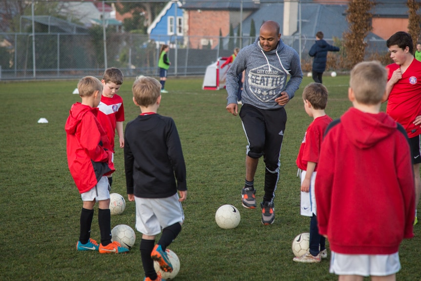 Former footballer Ahilan Ratnamohan (middle) is combining theatre and sport to teach Hobart children during workshops.