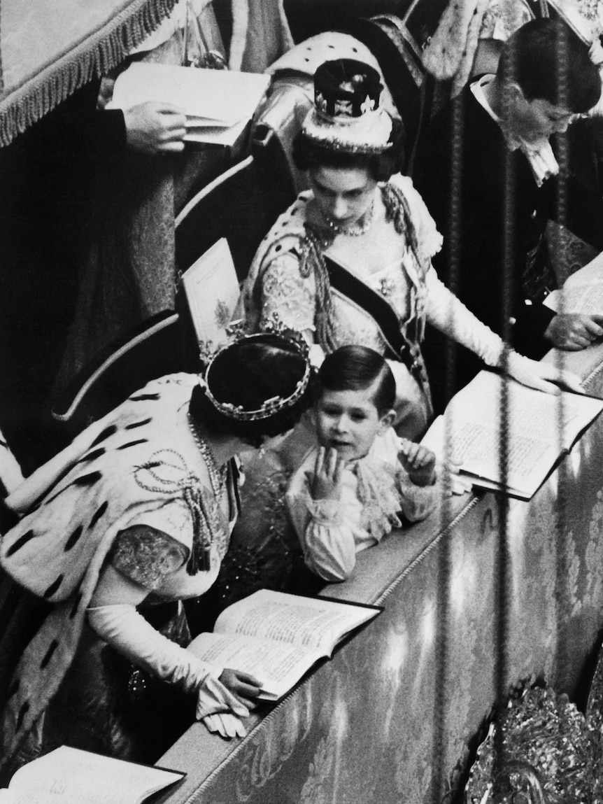 A black and white photo of four-year-old Charles with the Queen Mother and Princess Margaret at his mother's coronation.