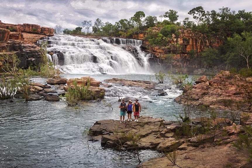 Group of people stand on edge of waterhole