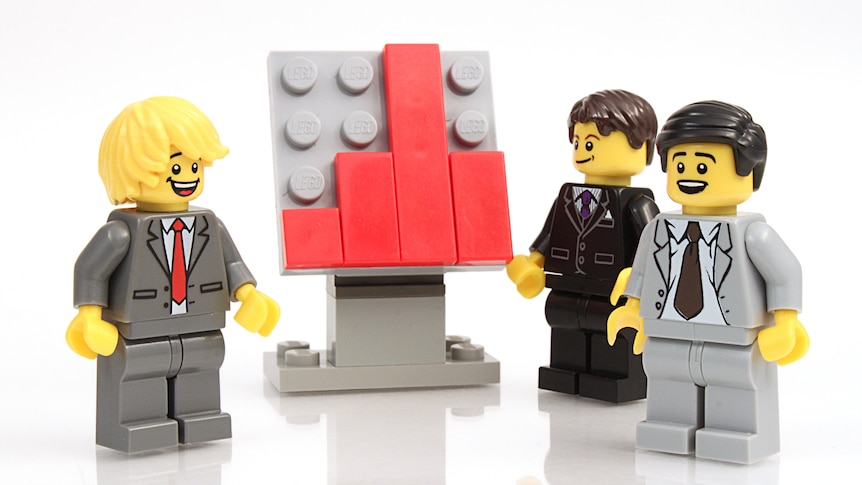 Threee Lego minifigures dresses as businessmen standing around a whiteboard