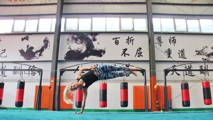 Amy Lyons does a one-handed handstand hold in a gym