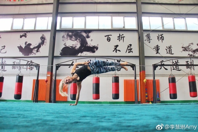 Amy Lyons does a one-handed handstand hold in a gym