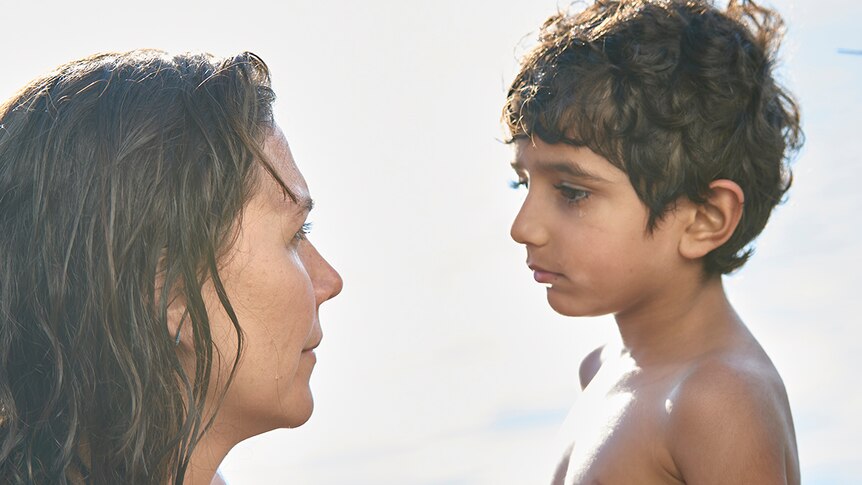 Colour close-up still of Maggie Gyllenhaal and Parker Sevak at the beach on sunny day in 2018 film The Kindergarten Teacher.