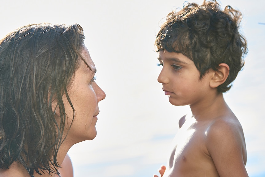 Colour close-up still of Maggie Gyllenhaal and Parker Sevak at the beach on sunny day in 2018 film The Kindergarten Teacher.