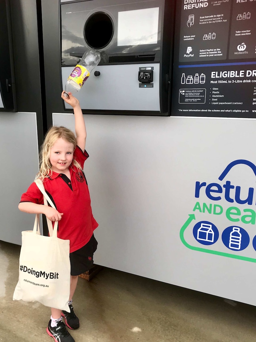 A 7-year-old girl puts a plastic bottle into a reverse vending machine