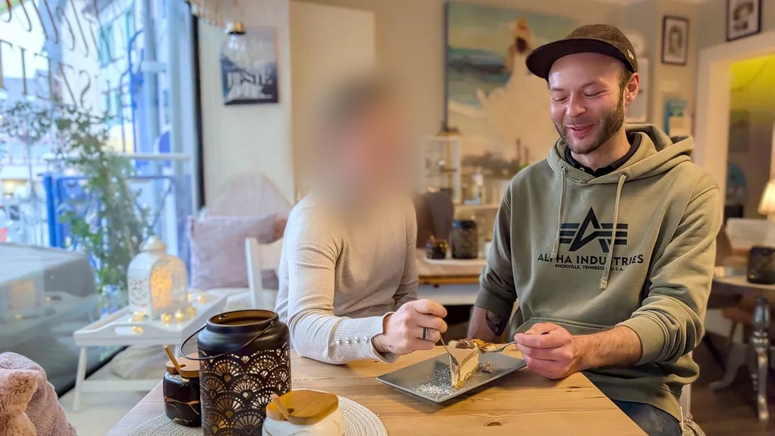 一对年轻男女坐在咖啡馆的桌旁吃蛋糕。