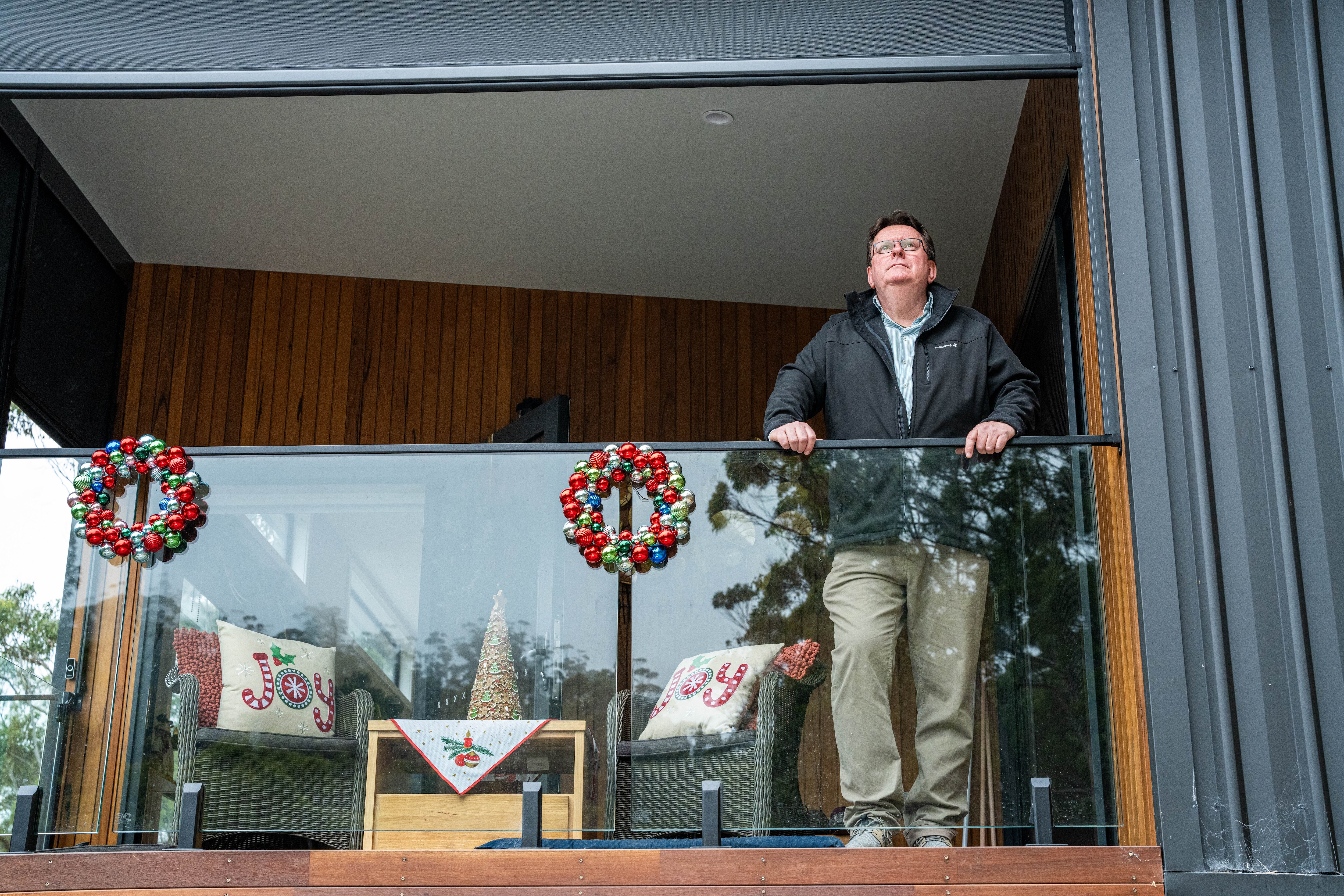 Man standing on the deck of his house.