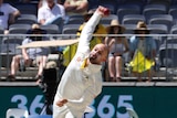 Australian bowlers Nathan Lyon bowls a ball during a Test at Perth Stadium. Umpire Kumar Dharmasena looks on.