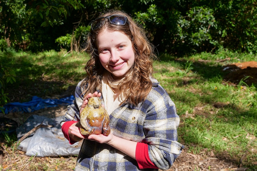 A young woman holds a fired ceramic ware in the form of a bear