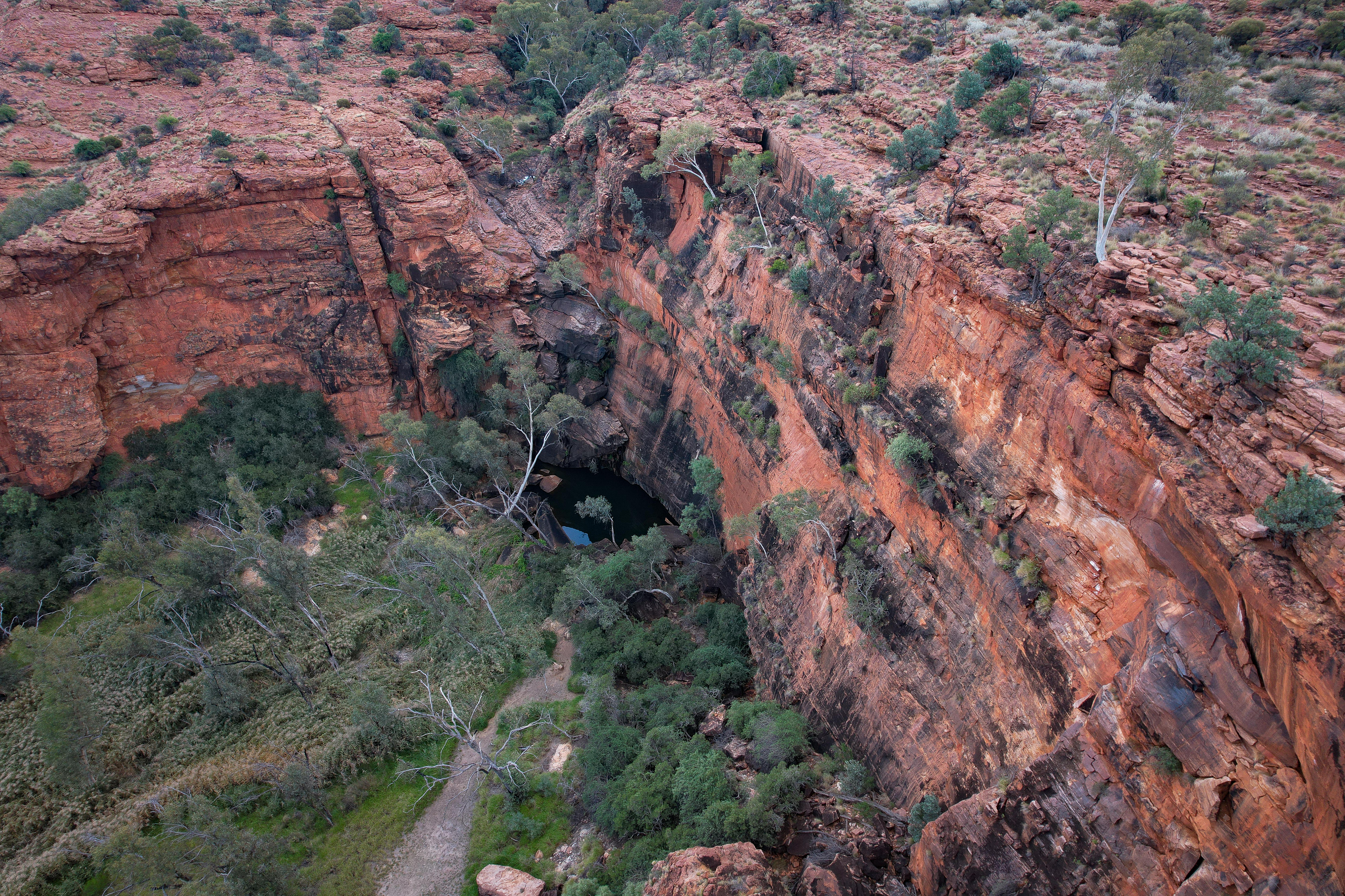 A view through a red rock canyon to a waterhole.