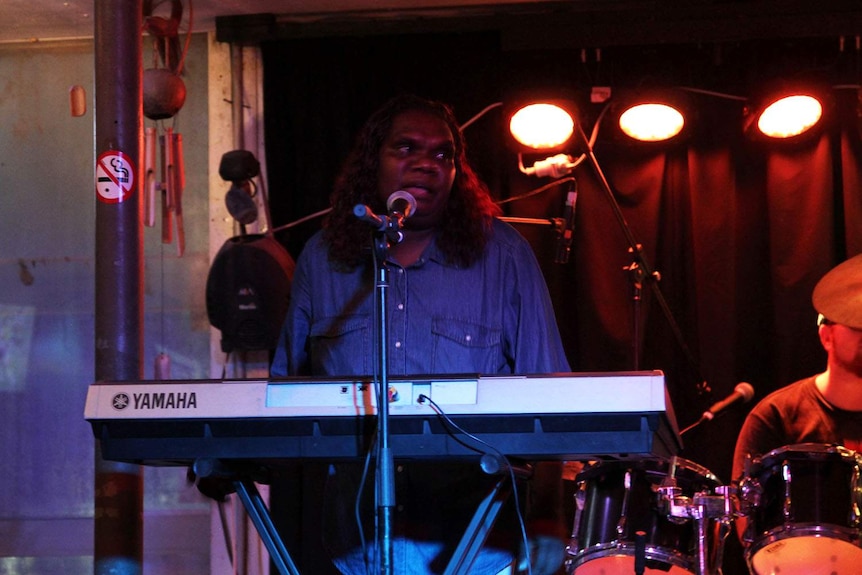 a woman singing on stage behind a keyboard