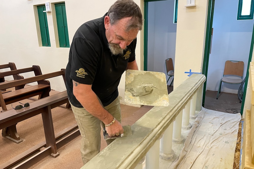 Man with trowel applies plaster inside a church
