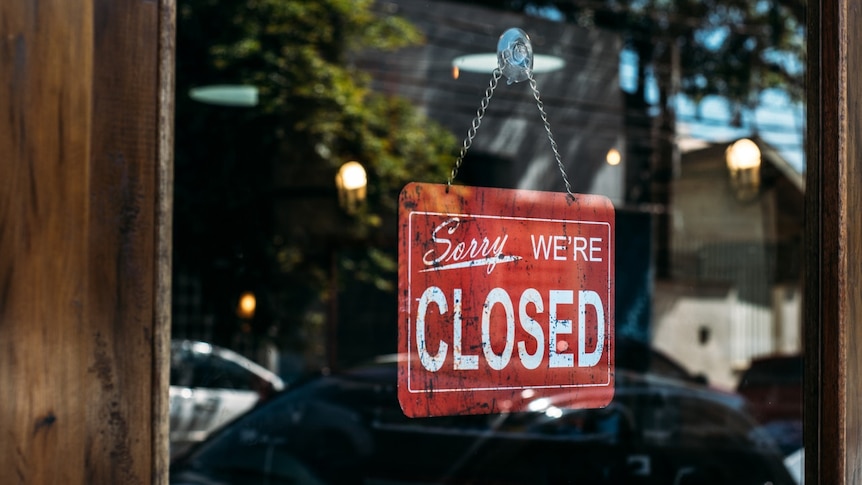 A closed sign in the door of a shop.
