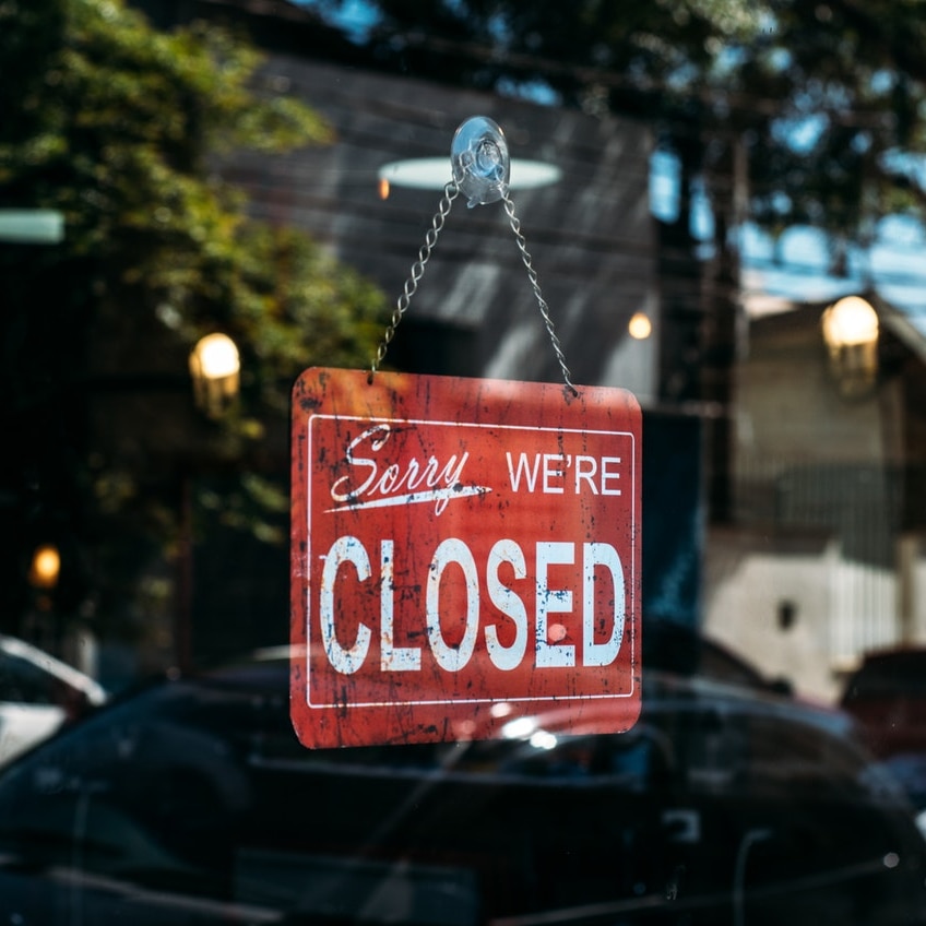 A closed sign in the door of a shop.