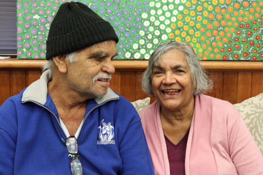 Man with beanie on head smiling on left, woman smiling on right