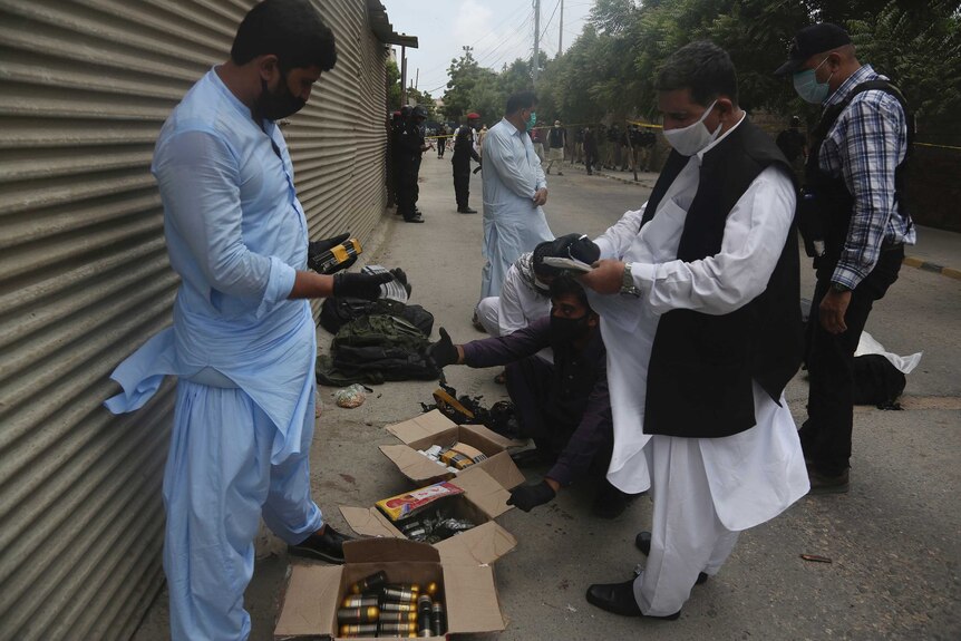 Security personnel examine confiscated ammunition from attackers outside the Stock Exchange Building in Karachi.