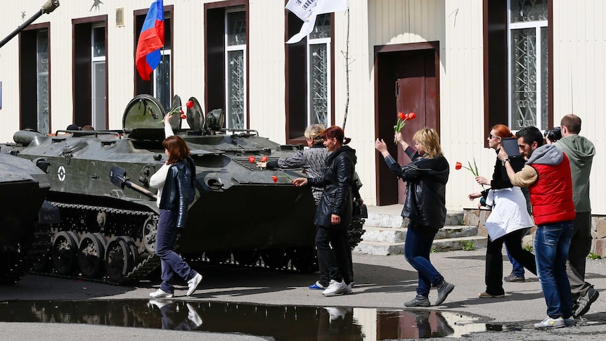 Locals place flowers on armoured personnel carriers