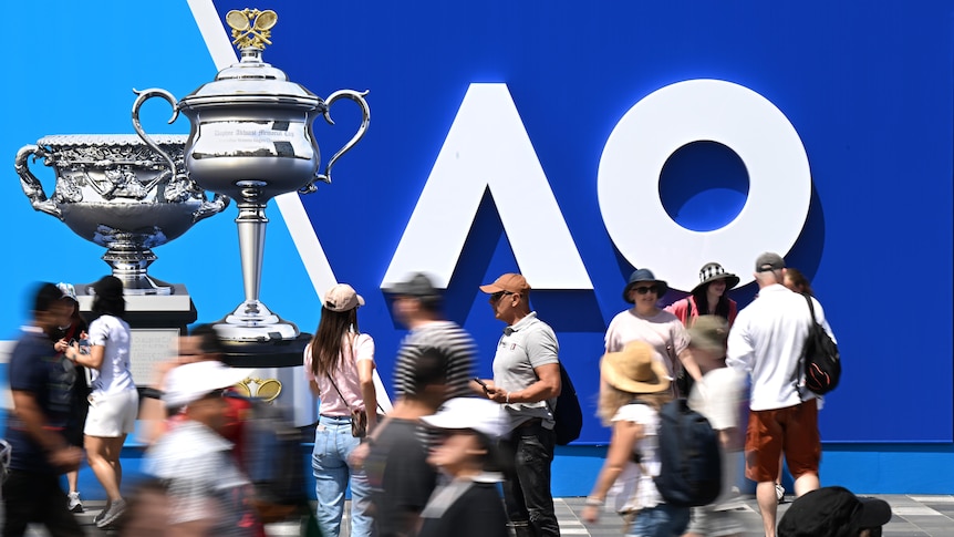People mill past Australian Open signage at the beginning of the tournament.