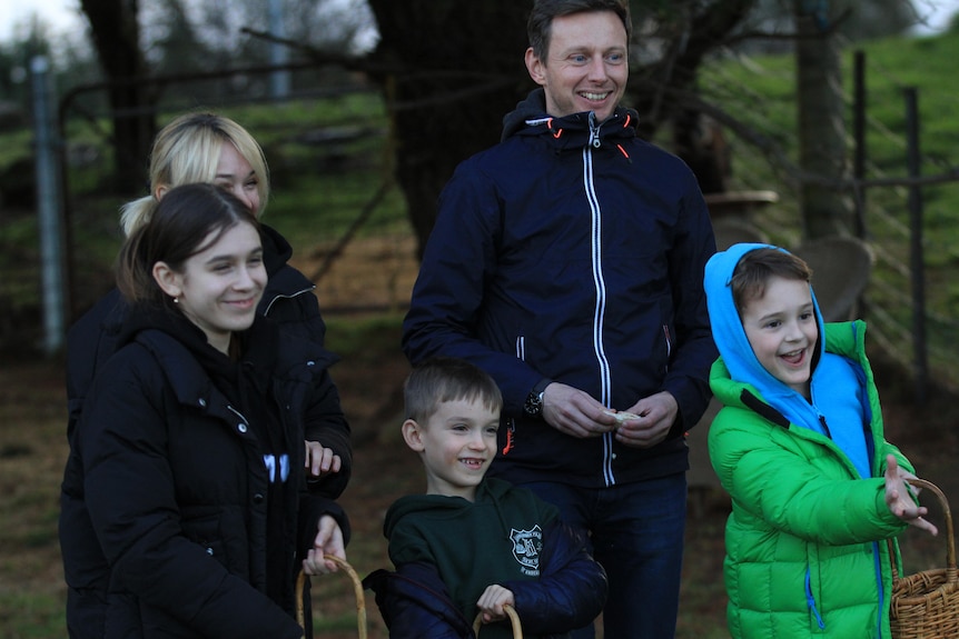 Man and wife with three children standing at a farm.