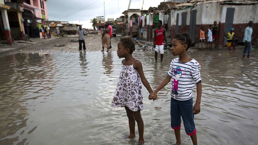 Girls hold hands amid Hurricane Matthew devastation