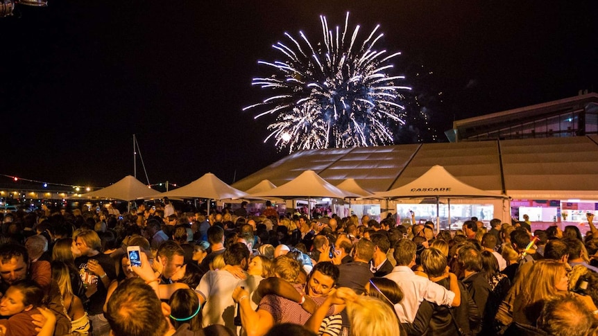 New Year's Eve crowd celebrates with fireworks overhead.