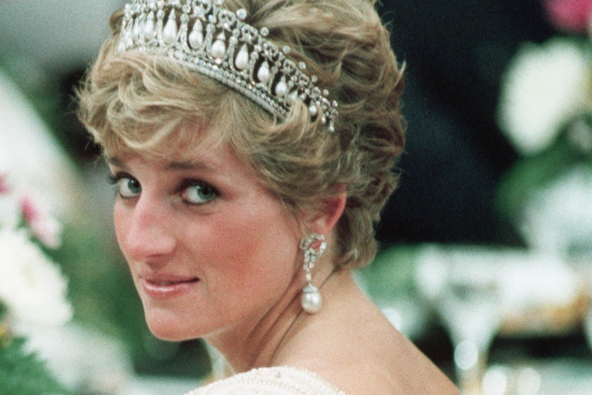 Princess Diana in a low-backed pearl gown and tiara looking over her shoulder