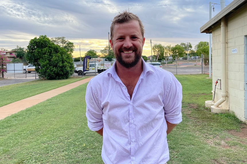 Man in white shirt, smiles at camera