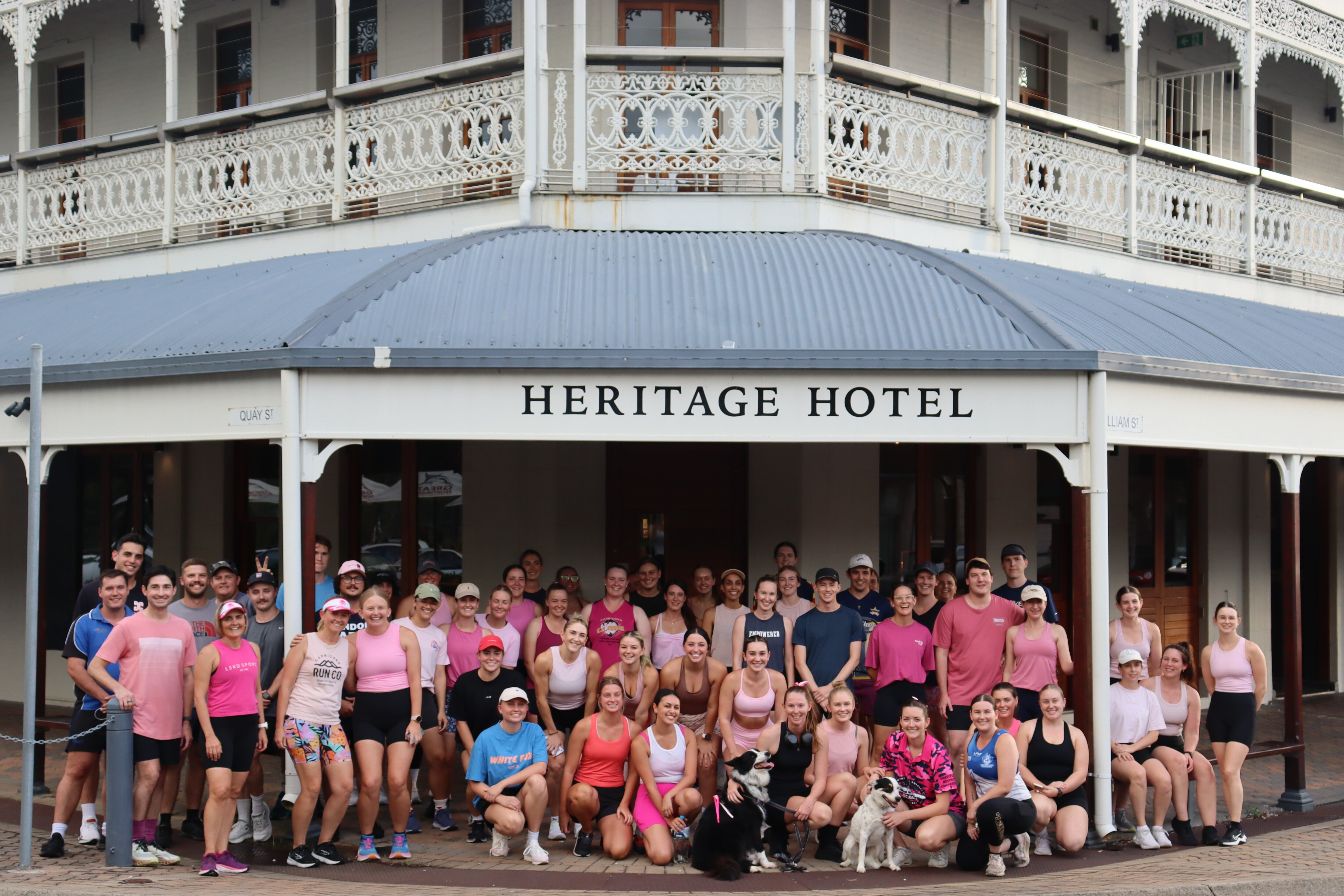 Fifty people in exercise gear smile at camera outside a pub