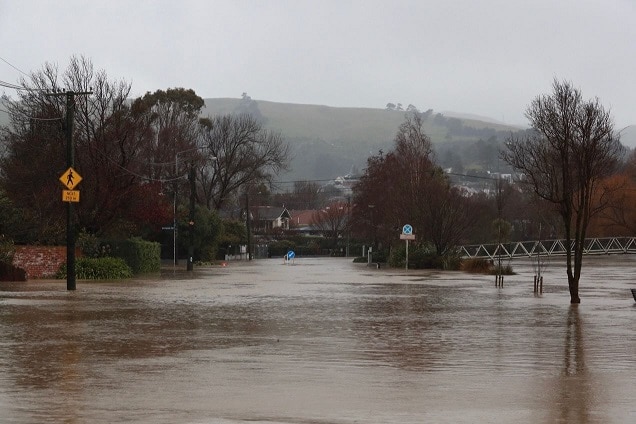 Flooded road in Christchurch with light rain falling and a hill in the background