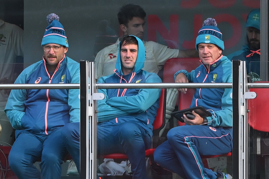 Daniel Vettori, Pat Cummins and Andrew McDonald wear warm clothes while watching an Ashes Test from the balcony at Old Trafford.