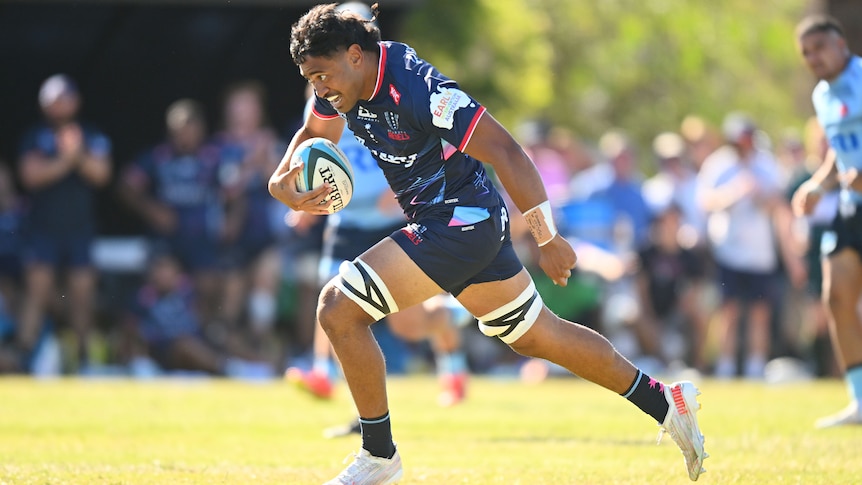 A Melbourne Rebels player runs with the ball during a preseason trial match.