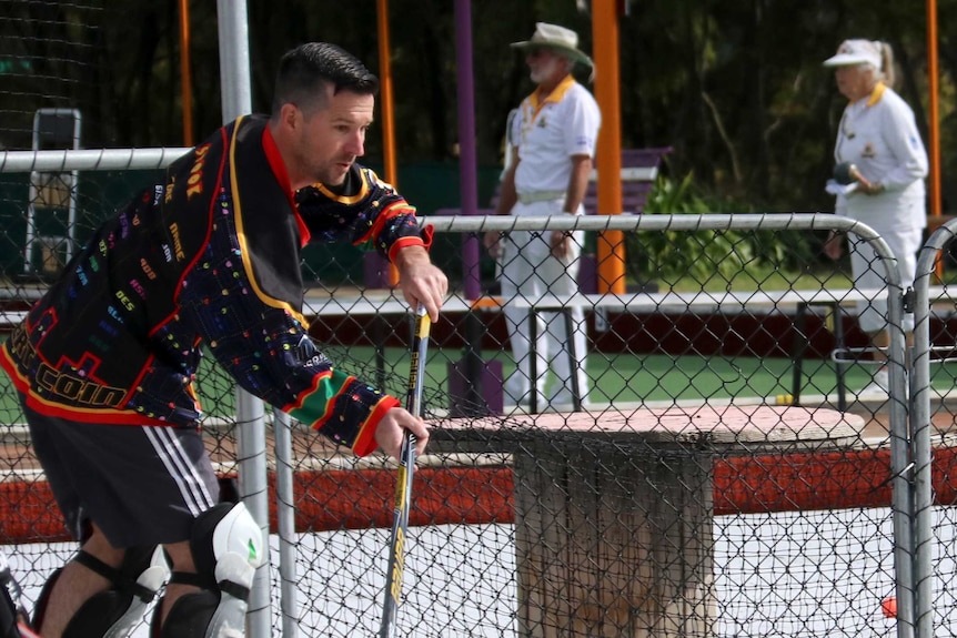 Roller hockey players play in front of bowls players at the club.