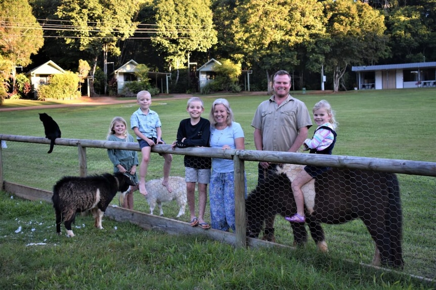 Family with animals beside a timber fence.