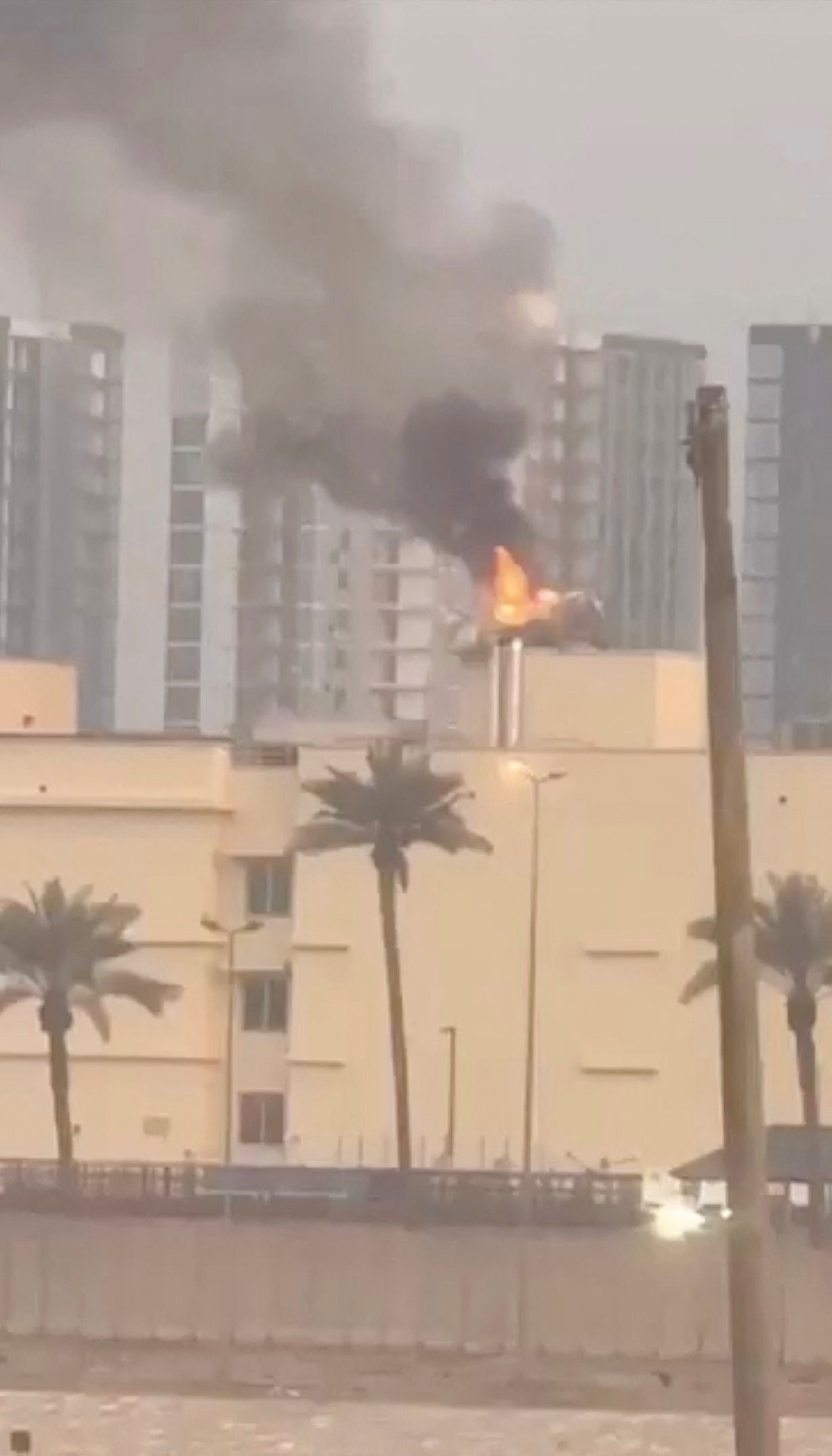 Se ven llamas en un edificio de una zona urbana, con una palmera en primer plano