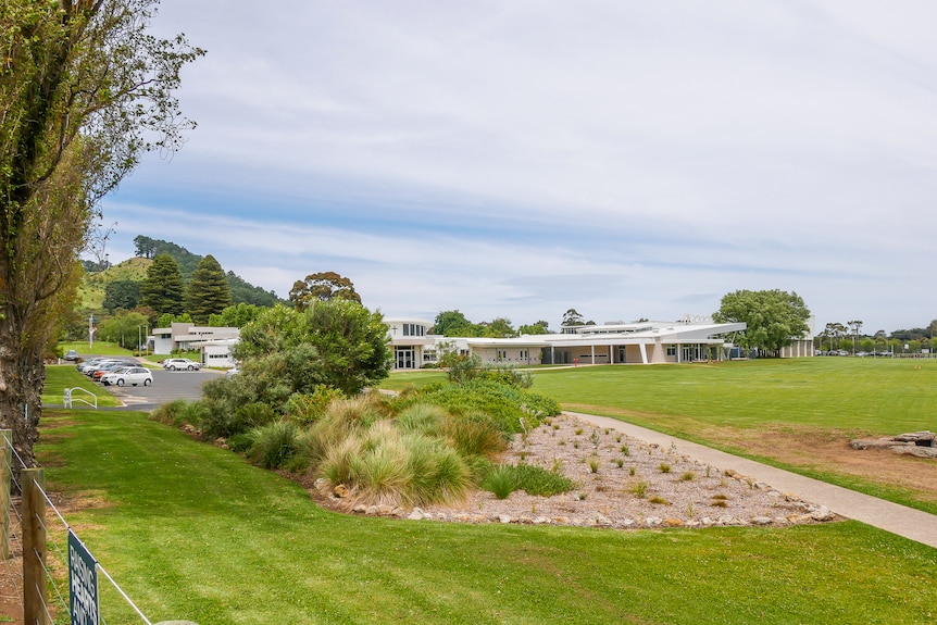 Lush green trees and a well-mowed lawn surround a white school chapel on a clear day.