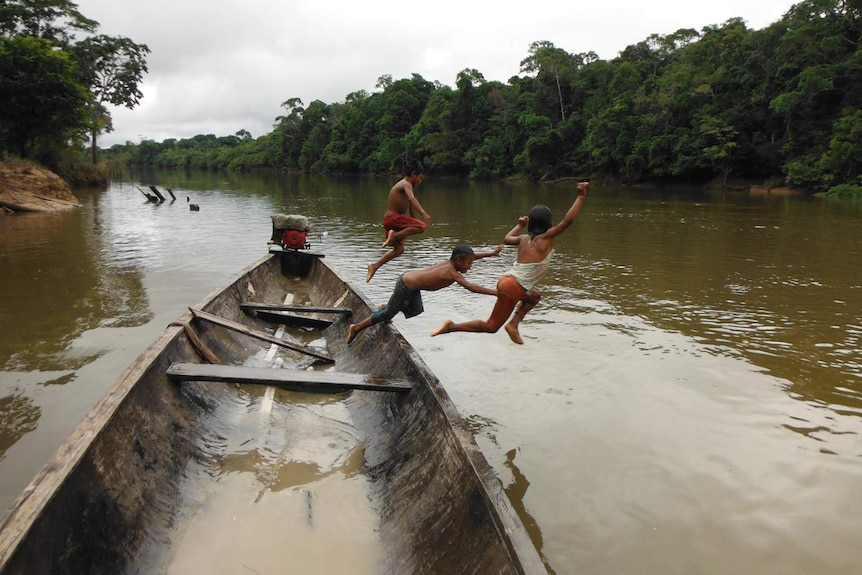 Three Murui children jump from a boat into the Cara-Paraná river.