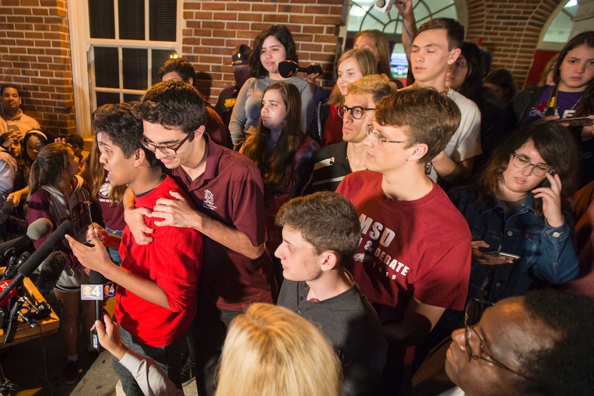 High School survivor Tanzil Philip, left, is comforted by fellow student Diego Pfeiffer as Philip speaks to Leon High School