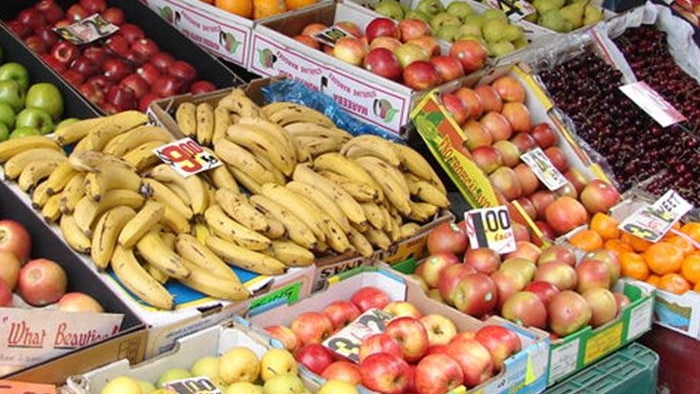 A fruit and vegetable stand with apples, bananas and mandarins.